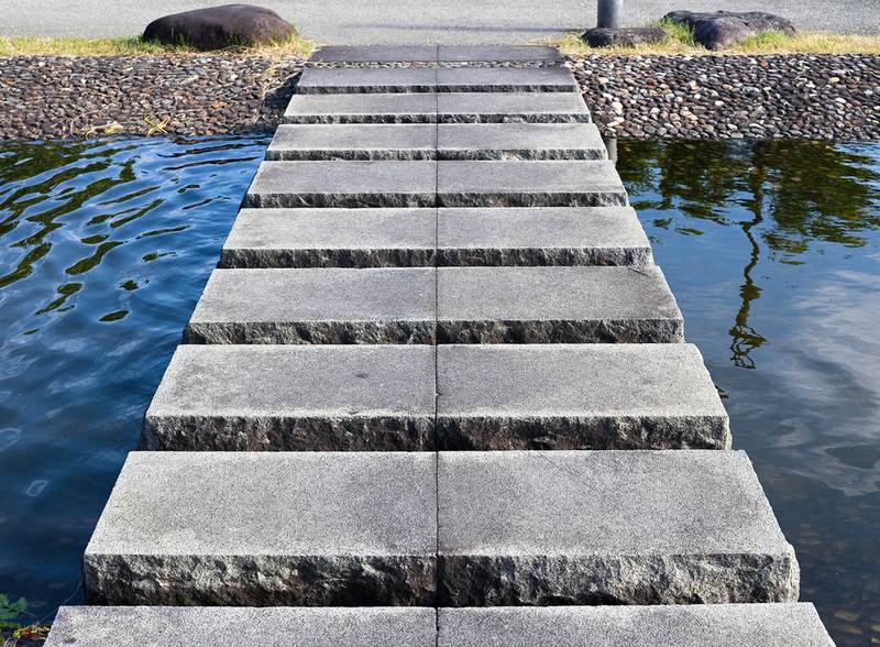 Flat granite stepping stones crossing still water to the far bank